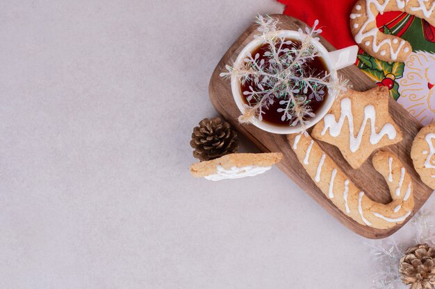 Biscuits de Noël avec du thé aromatique en tasse sur une surface blanche