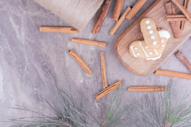 Biscuits de pain d'épice avec des bâtons de cannelle sur une longue planche de bois.