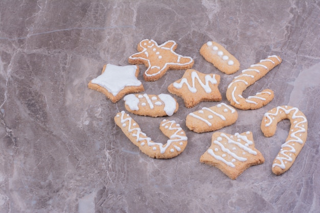 Biscuits en pain d'épice en forme d'étoile, de bâton et ovale sur marbre.