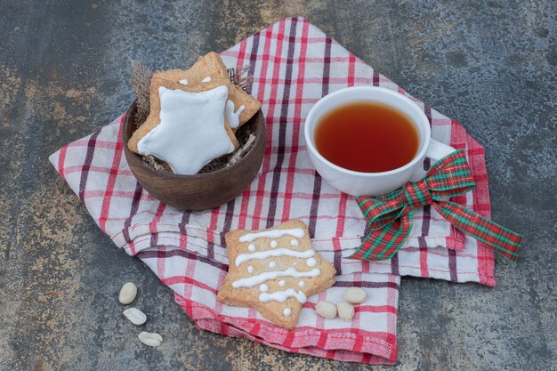 Biscuits en pain d'épice en forme d'étoile et tasse de thé sur la nappe. Photo de haute qualité