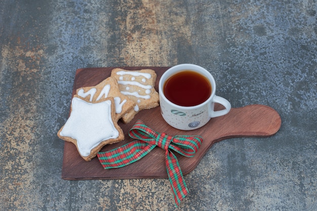 Biscuits en pain d'épice en forme d'étoile et tasse de thé sur planche de bois. Photo de haute qualité