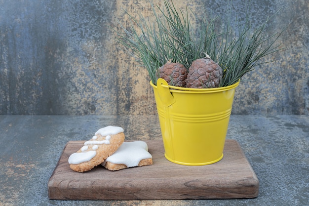 Photo gratuite biscuits de pain d'épice et pommes de pin sur planche de bois. photo de haute qualité