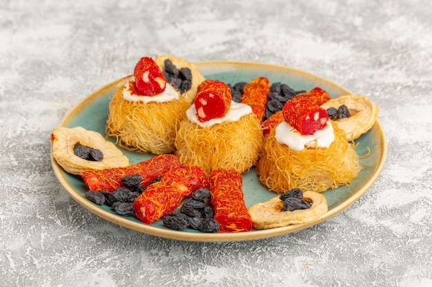 Biscuits pâtissiers de l'Est à l'intérieur de la plaque verte avec des fruits secs à la crème blanche et peu de confitures