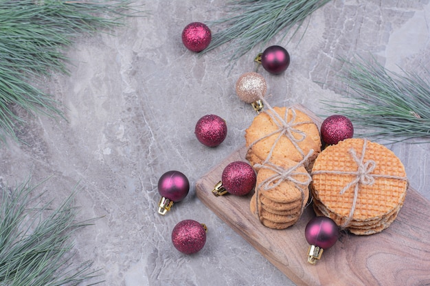 Biscuits sur une planche de bois avec des boules de Noël paillettes rouges autour