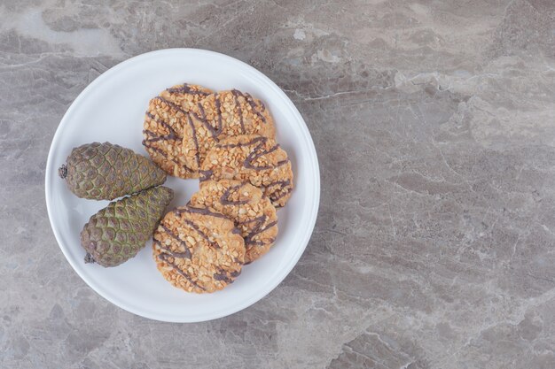 Biscuits et pommes de pin sur un plateau sur marbre