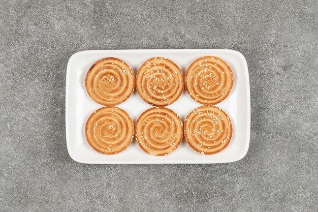 Biscuits ronds aux graines de sésame sur plaque carrée blanche