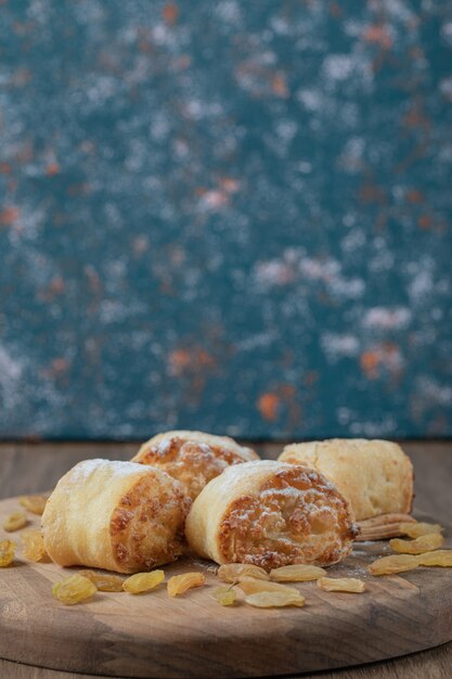 Biscuits roulés frits aux raisins blancs et farces sucrées sur une planche de bois.