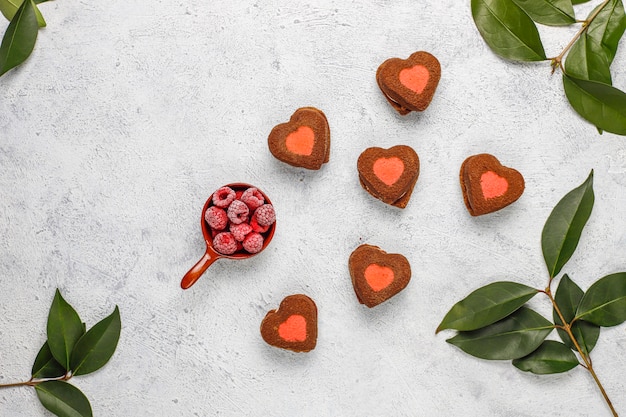 Biscuits de Saint Valentin en forme de coeur avec des framboises surgelées à la lumière