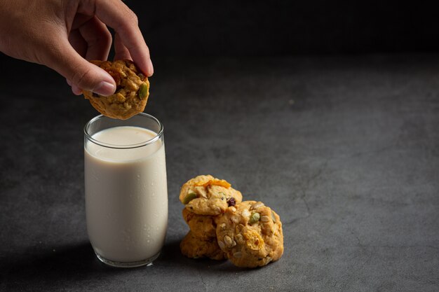 Photo gratuite biscuits servis avec un verre de lait sur un sol sombre