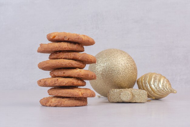 Biscuits sucrés avec des boules de Noël dorées sur une surface blanche