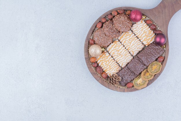 Biscuits sucrés et boules de Noël sur planche de bois.