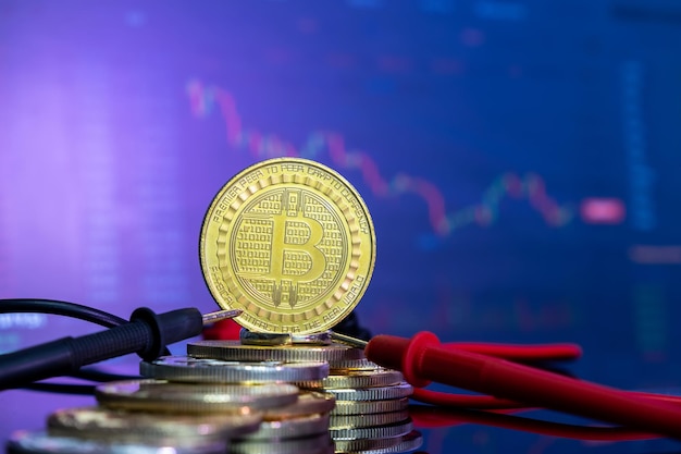 Bitcoin doré sur une surface réfléchissante bleue au-dessus d'autres pièces et l'histogramme de la monnaie