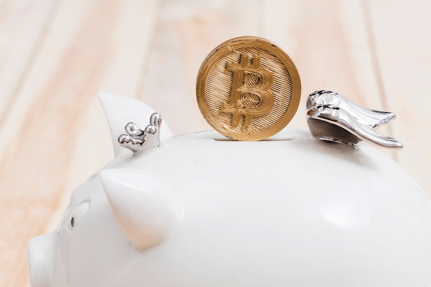 Bitcoins dorés sur la fente de la tirelire blanche