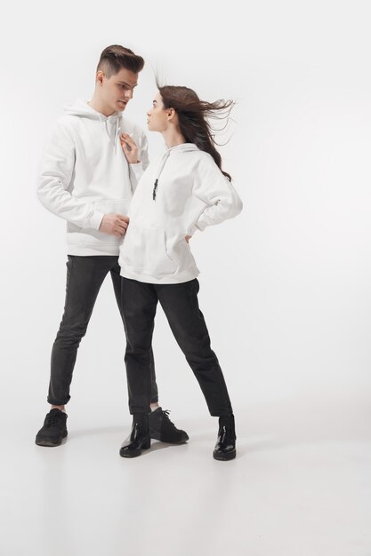 En blanc. Couple à la mode à la mode isolé sur le mur du studio blanc.