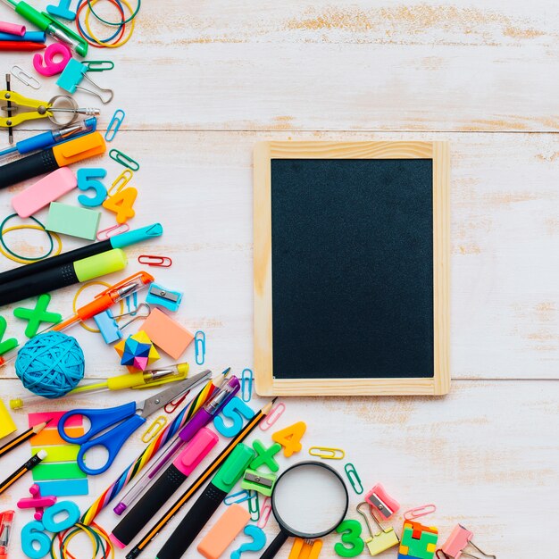 Blanc petit tableau avec un groupe de fournitures scolaires sur un fond en bois blanc