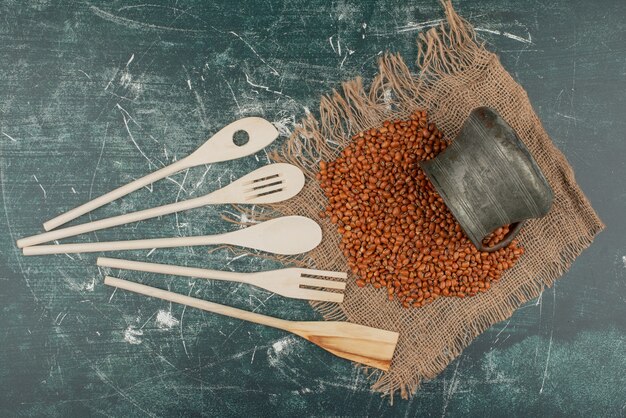 Blé sur toile de jute avec des ustensiles de cuisine sur une surface en marbre.