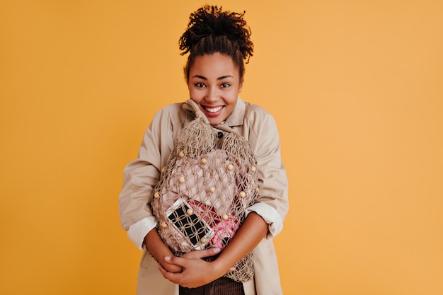 Blithesome jeune femme tenant un sac à cordes et souriant