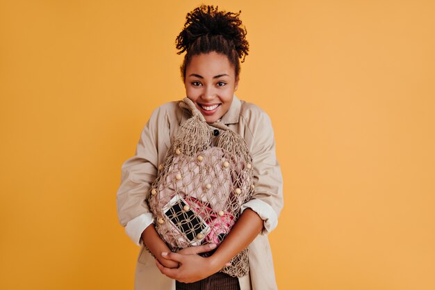 Blithesome jeune femme tenant un sac à cordes et souriant