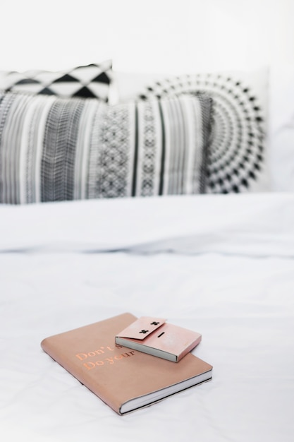 Photo gratuite bloc-notes collant sur le livre sur le lit blanc