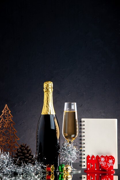 Bloc-notes d'ornements de Noël de bouteille de verre de champagne vue de face sur une surface sombre