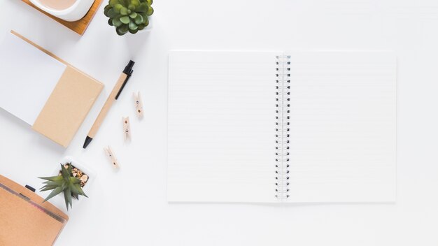 Bloc-notes près de papeterie et de pots de fleurs sur une table blanche