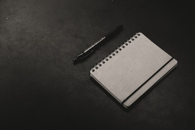 Un bloc-notes avec un stylo sur un fond sombre