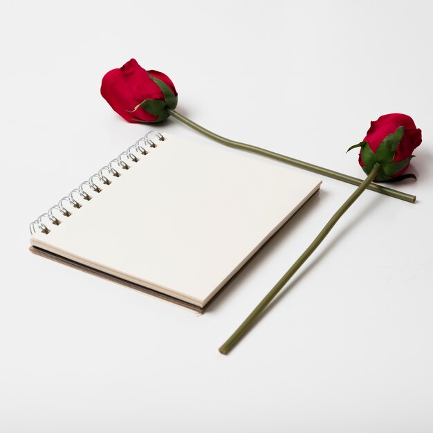 Photo gratuite bloc-notes vide avec des roses sur la table