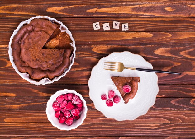 Blocs de texte de gâteau sur la tranche de gâteau et de framboise sur une plaque blanche avec une fourchette