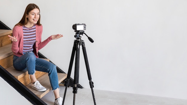 Blogger enregistrement avec caméra et assis sur les escaliers