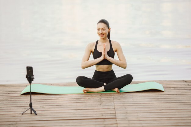 Blogger pratiquant le yoga avancé au bord de l'eau