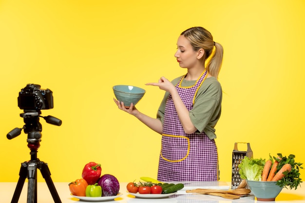 Photo gratuite blogueur culinaire adorable chef en bonne santé enregistrant une vidéo pour les médias sociaux pointant vers un bol