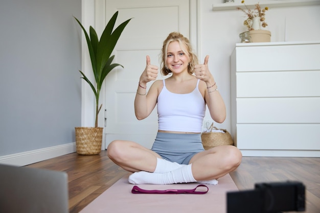 Photo gratuite blogueur de fitness en bonne santé et en forme enregistrant un vlog pour le bien-être compte de médias sociaux assis sur le yoga