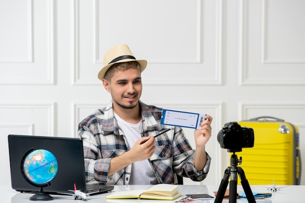 Photo gratuite blogueur de voyage portant un chapeau de paille jeune beau mec enregistrant un vlog de voyage sur une caméra tenant un billet