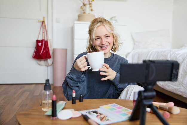 Une blogueuse de beauté joyeuse enregistre un vlog de style de vie sur une caméra numérique, parle et raconte casuellement une histoire.