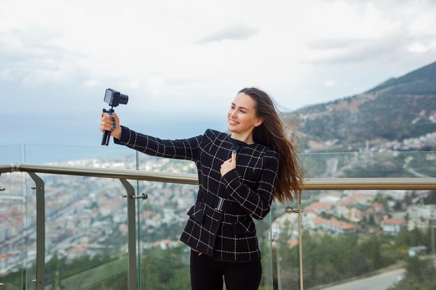 Une blogueuse heureuse prend un selfie en se montrant avec la main sur fond de vue sur la ville