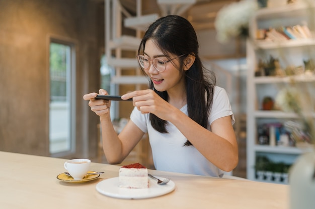 Une blogueuse influenceuse asiatique amicale mange un gâteau au café de nuit