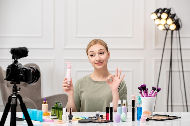 Blogueuse de maquillage créant un tutoriel de maquillage vlog sur caméra jeune jolie jolie fille tenant une nouvelle crème