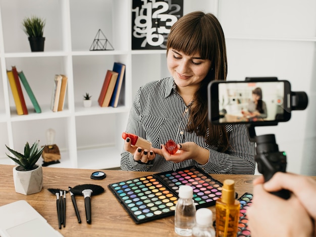 Photo gratuite blogueuse de maquillage féminin avec streaming avec smartphone à la maison