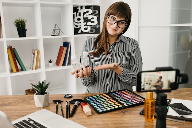 Blogueuse de maquillage féminin avec streaming avec smartphone et ordinateur portable à la maison