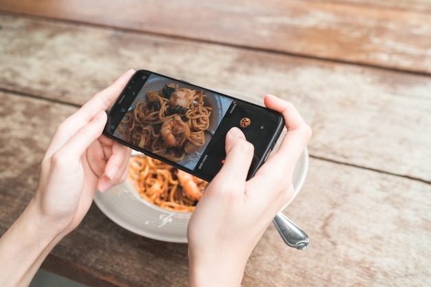 Une blogueuse photographiant le déjeuner au restaurant avec son téléphone