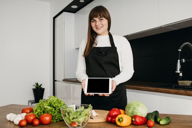 Blogueuse s'enregistrant tout en préparant une salade avec tablette