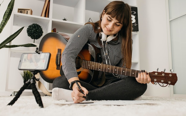 Photo gratuite blogueuse en streaming des cours de guitare avec smartphone
