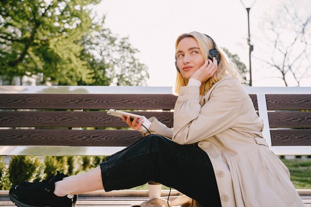 Blonde assise sur un banc avec téléphone portable