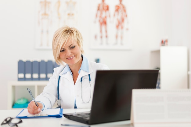 Blonde belle femme médecin travaillant dans son bureau