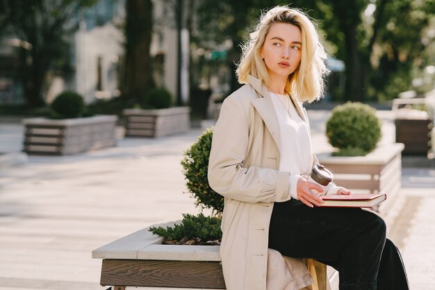 Blonde dans une ville d'été avec une tasse de café