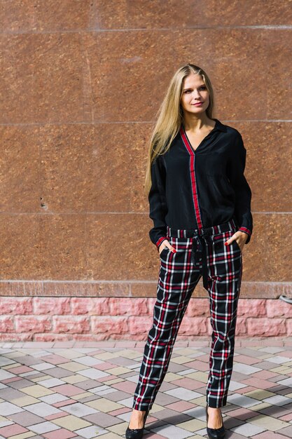 Blonde élégante jeune femme debout devant le mur