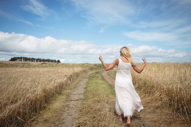 Blonde femme marchant sur le chemin dans le champ