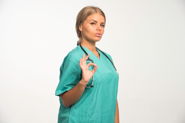 Photo gratuite blonde femme médecin en uniforme bleu avec stéthoscope dans le cou semble puissante