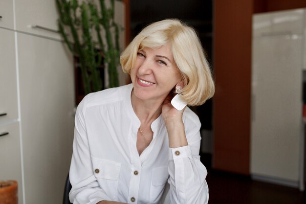 Blonde femme tenant une tasse de thé et assis dans une cuisine moderne