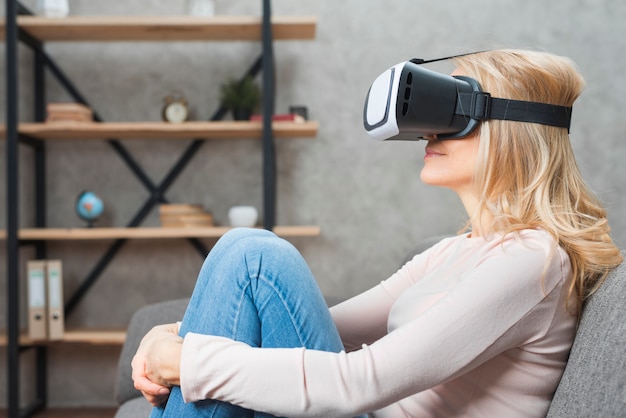 Photo gratuite blonde jeune femme assise sur le canapé portant des lunettes de réalité virtuelle